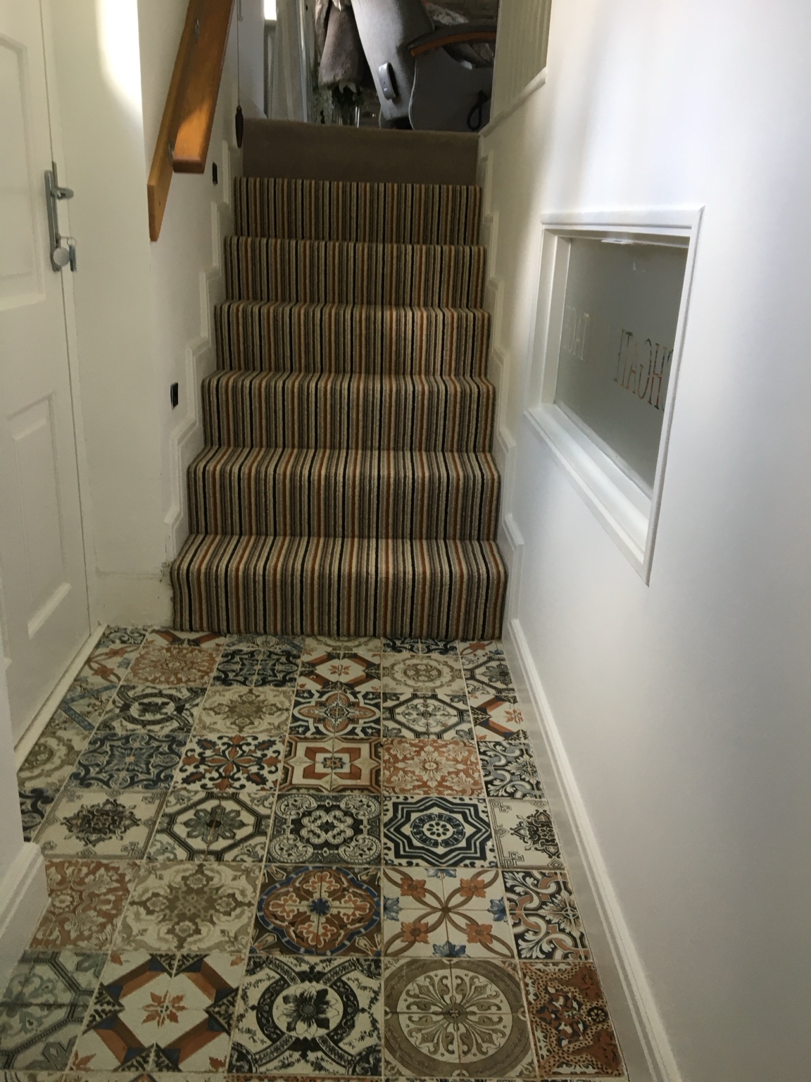 Striped stair carpet beside patterned hallway flooring