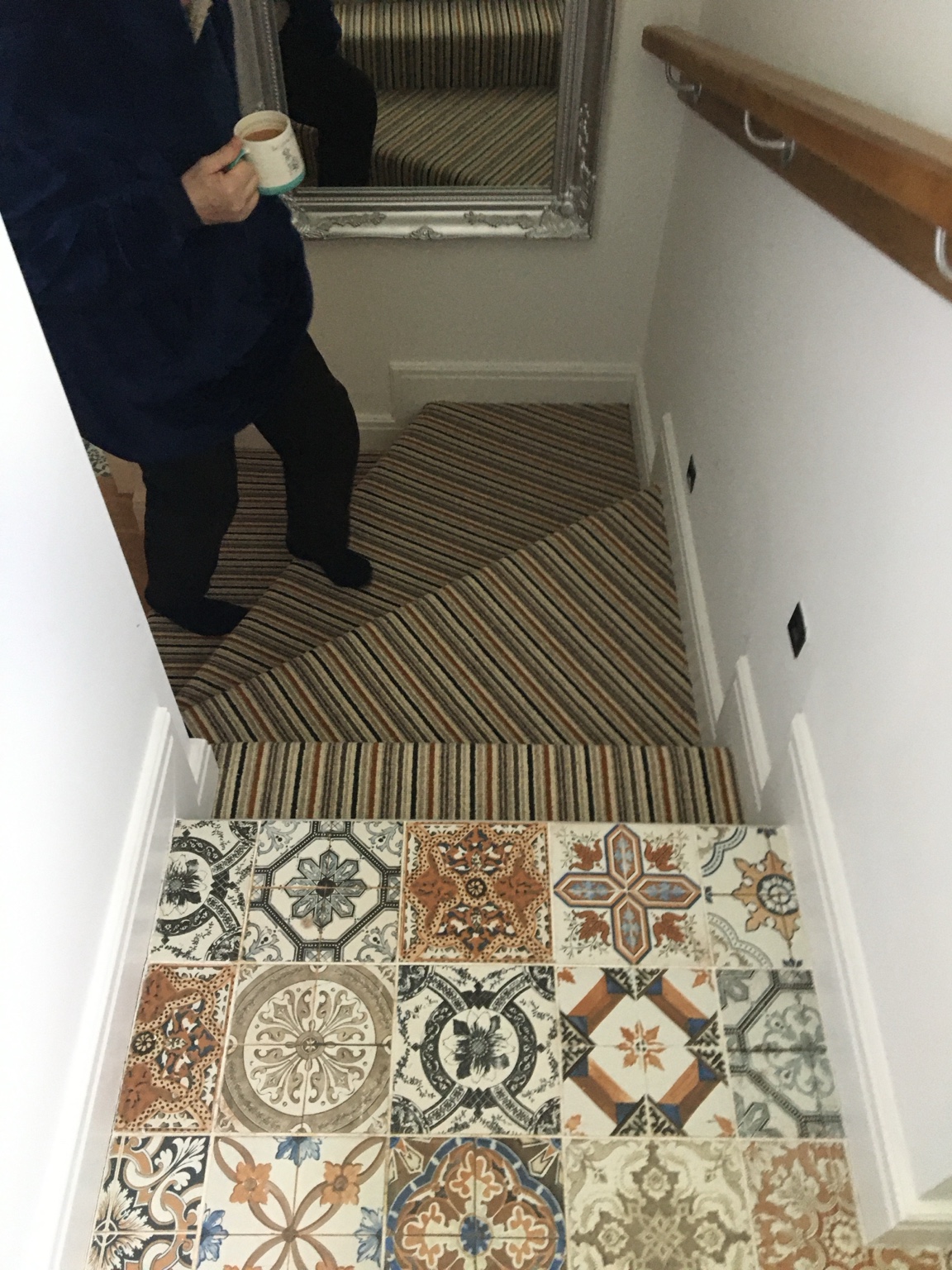 Striped carpet meeting a decorative patterned hallway floor