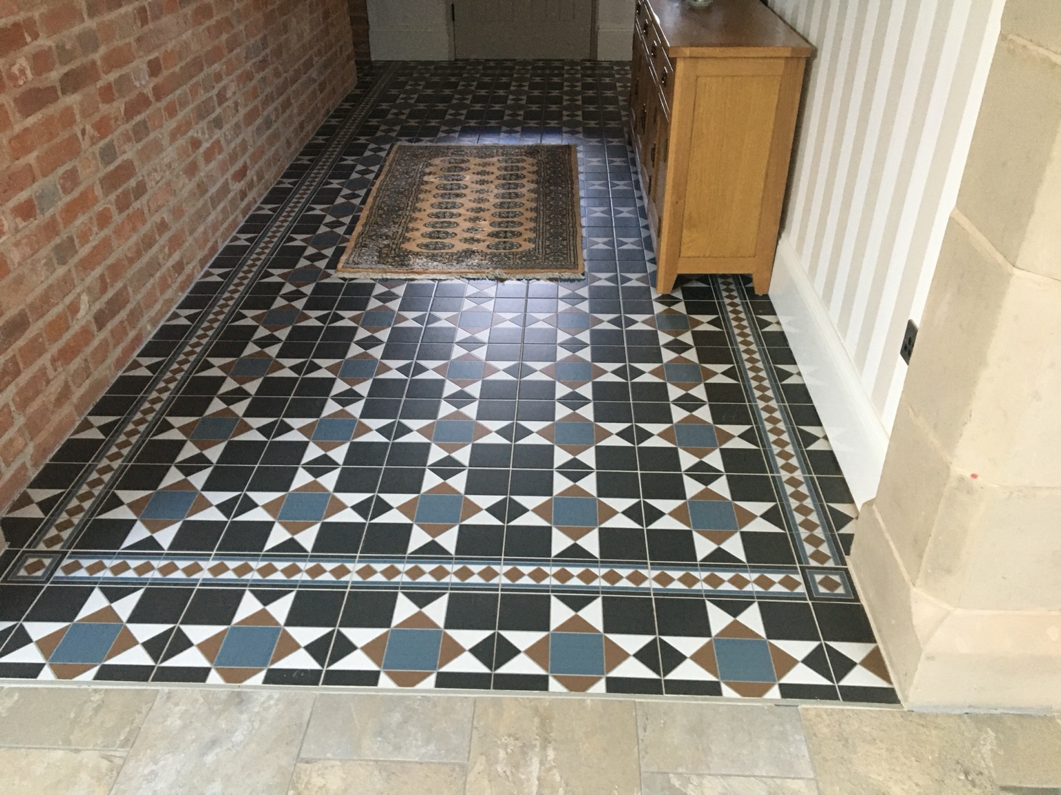 Decorative patterned flooring in a hallway with an exposed brick wall